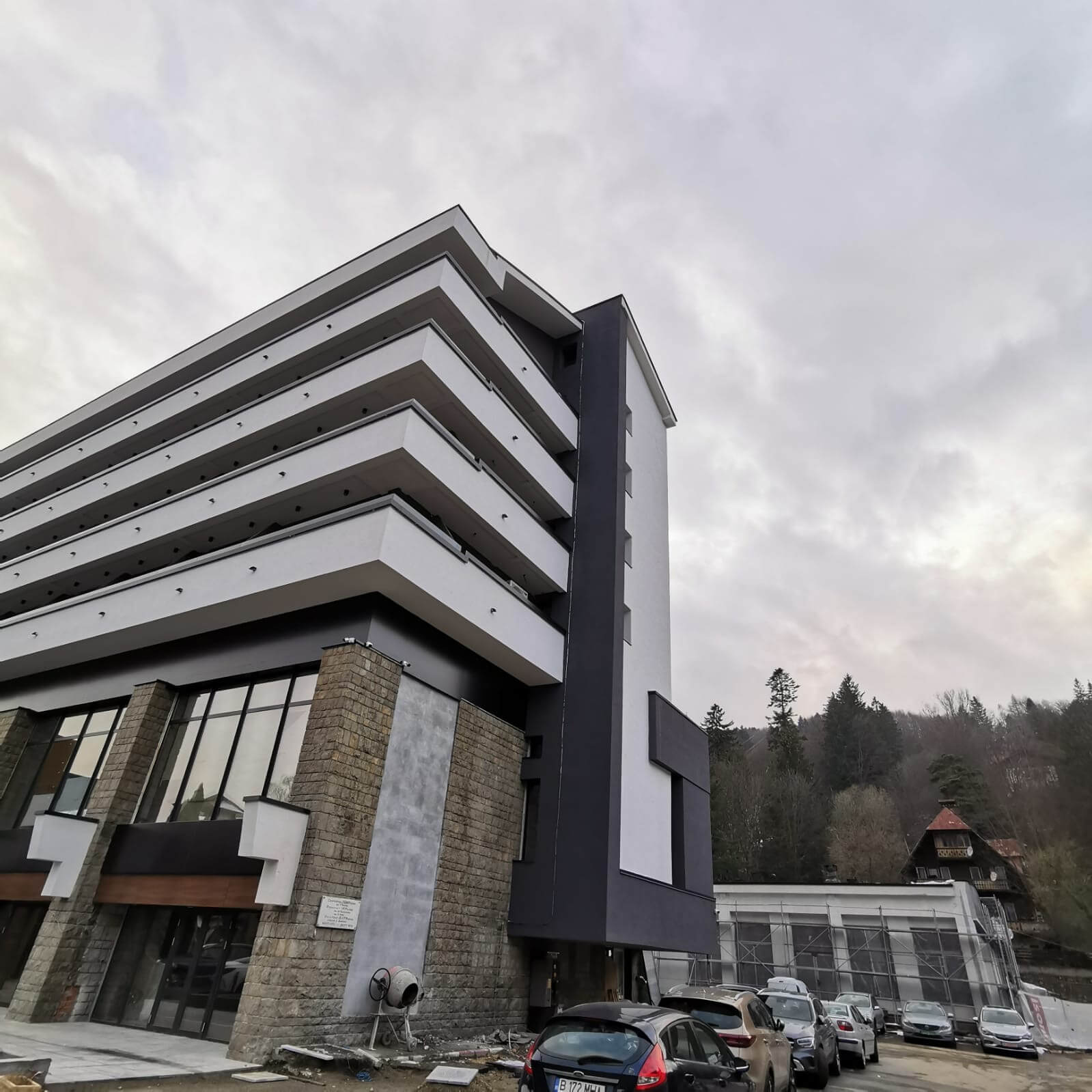 Fațadă a unei clădiri rezidențiale cu balcoane placate în aluminiu, în zonă montană
