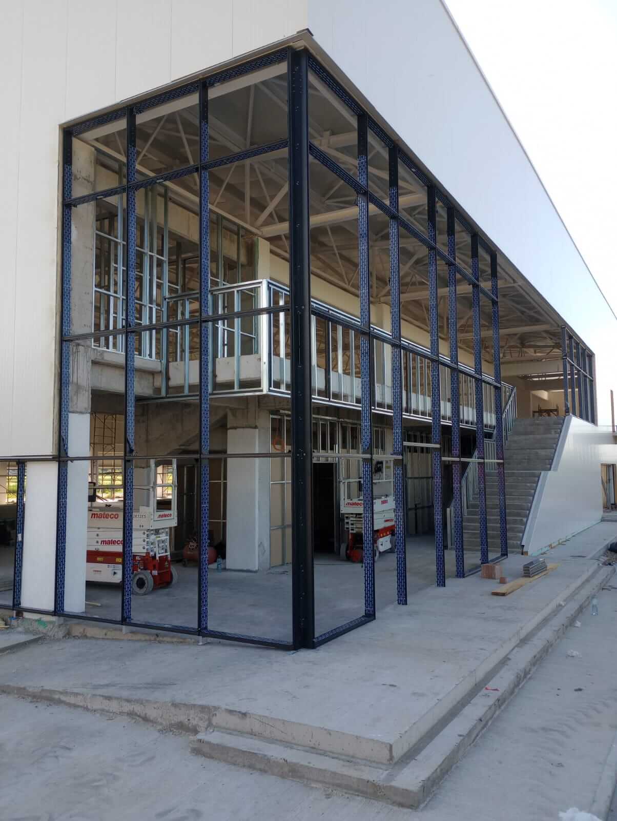Montaj perete cortină din sticlă și aluminiu pe o clădire industrială, structură metalică vizibilă