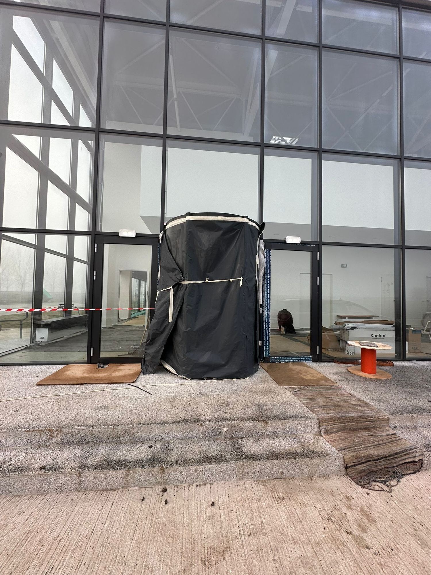 Intrare cu uși duble din sticlă și aluminiu, protejate în timpul lucrărilor de finisare